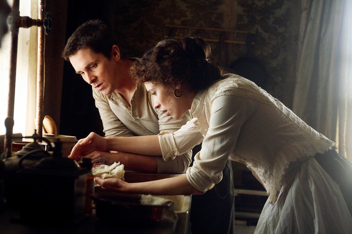 Christian Bale and Rebecca Hall in The Prestige, leaning over a table