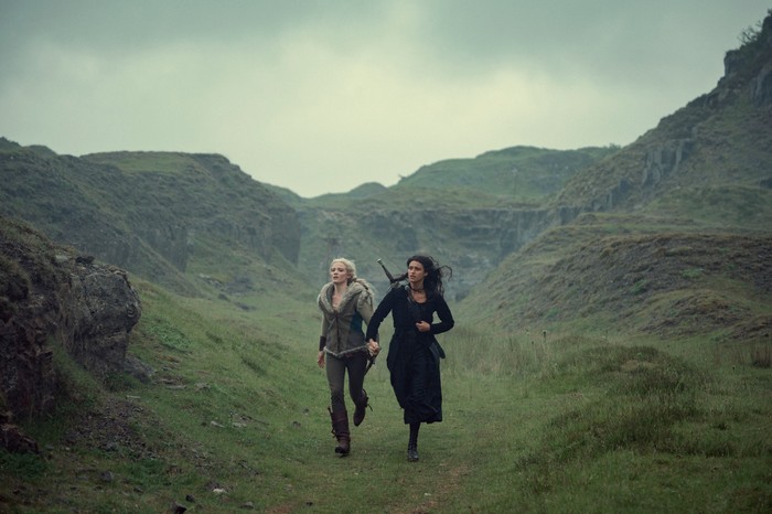 Ciri and Yennefer running through a hilly environment