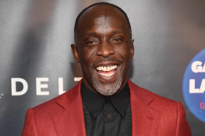 Michael K Williams in a red suit jacket and black shirt