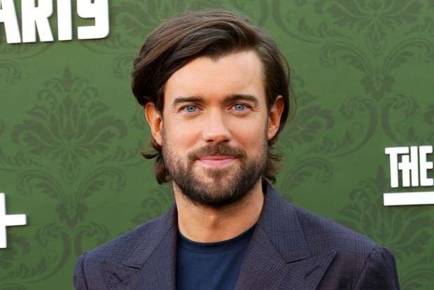 Jack Whitehall in a navy t-shirt and grey suit jacket
